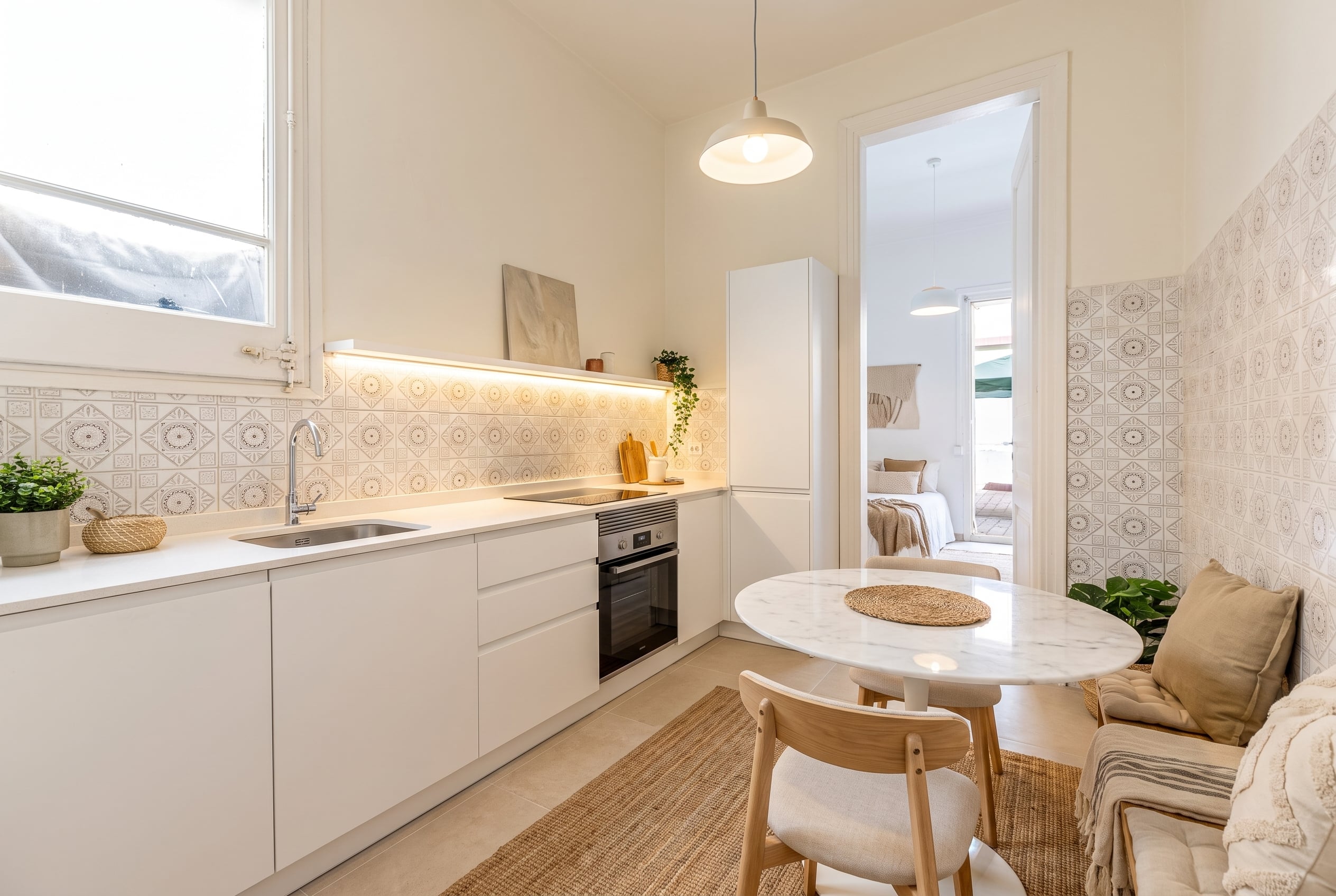 Cocina blanca renovada con comedor después de reforma visual inmobiliaria