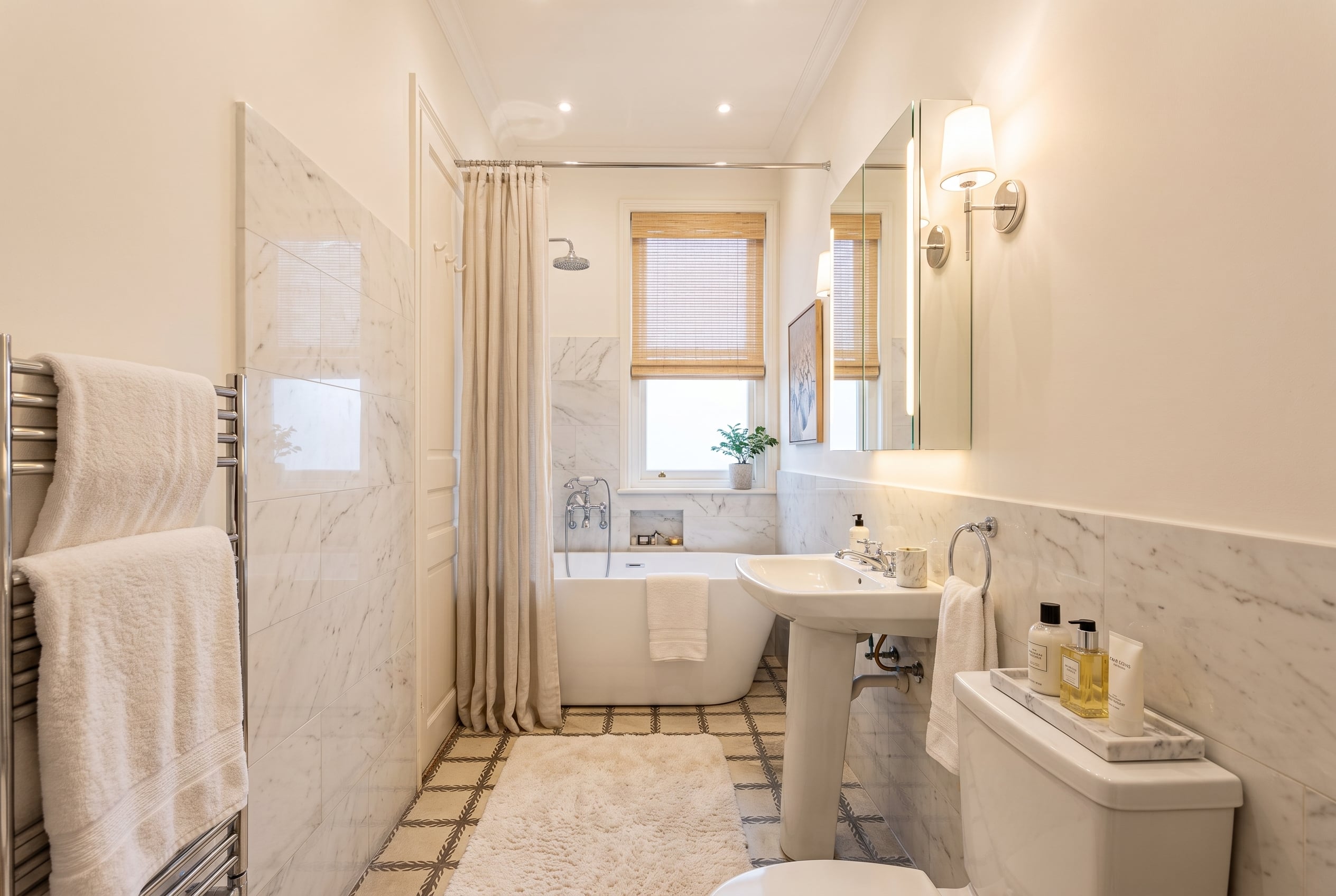 Baño renovado con mármol y luz cálida después de reforma visual inmobiliaria